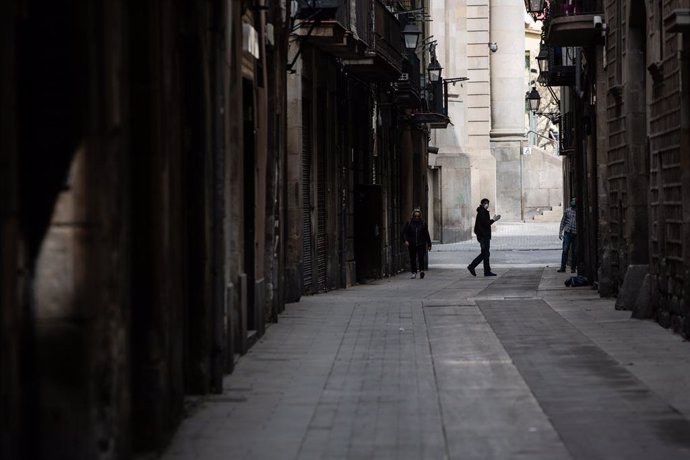 Una persona camina per un carrer de Barcelona durant el tercer dia laborable de l'estat d'alarma per coronavirus, a Barcelona