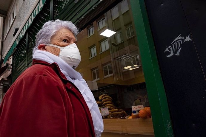 Una mujer espera en la entrada de un local comercial durante el estado de alarma provocado por la crisis del coronavirus