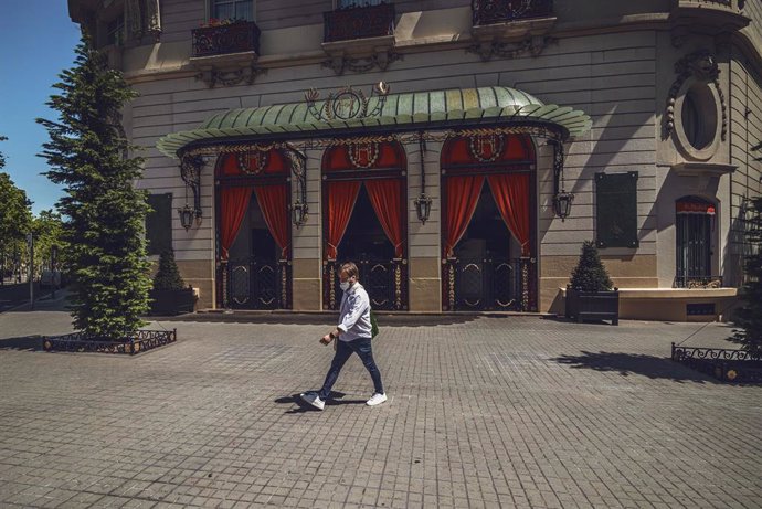 Un hombre camina por delante del hotel 'El Palace', en Barcelona, cerrado durante la crisis del coronavirus.