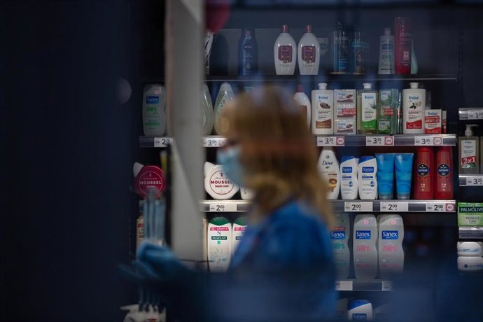 Una mujer protegida con mascarilla y guantes trabaja en una tienda