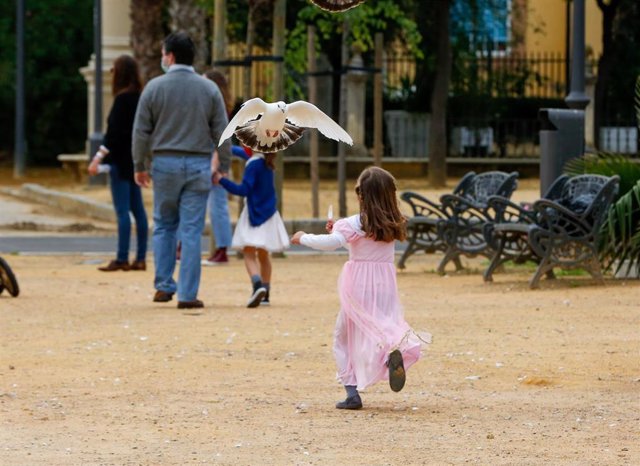 Una paloma se acerca a una niña en el Parque de Maria Luisa, en el primer día que los niños han podido salir acompañados de un adulto. Sevilla a 26 de abril del 2020