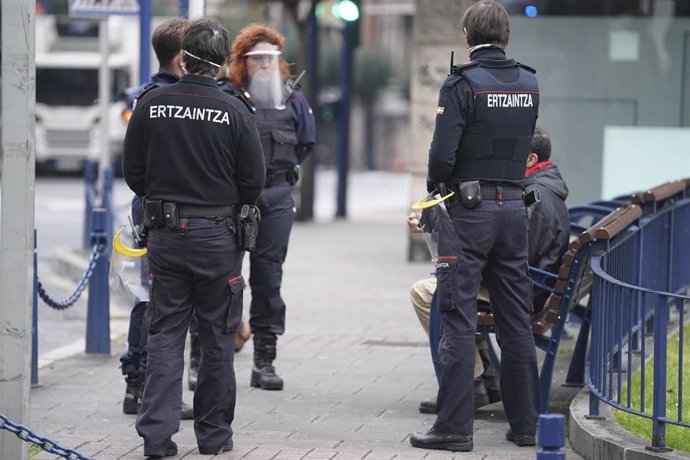 Efectivos de la Ertzaintza le piden la documentación a una persona que se encontraba en un banco en pleno estado de alarma por coronavirus en Bilbao, País Vasco, (España), a 31 de marzo de 2020.