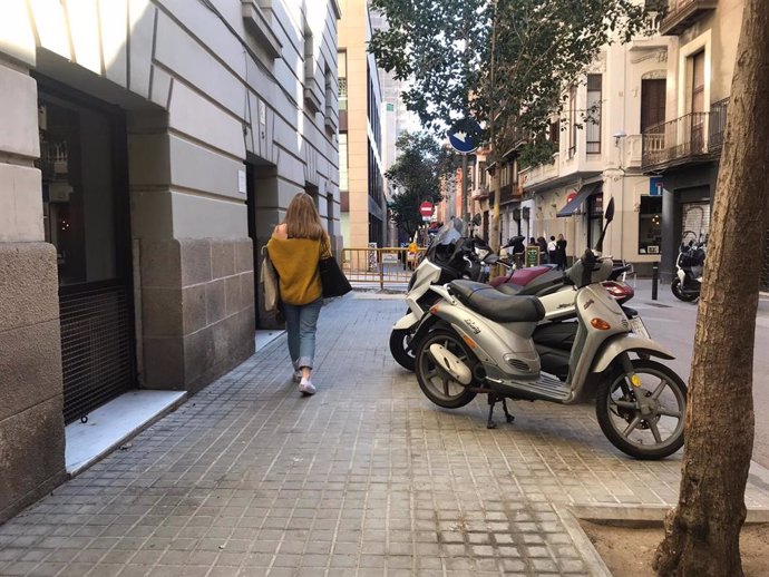 Motos aparcadas en la acera en una calle del barrio de la Vila de Grcia