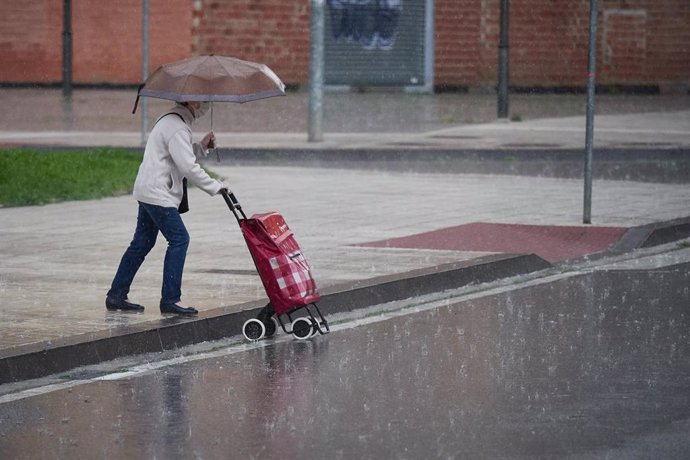 Una mujer regresa de hacer la compra en plena lluvia durante el Estado de Alarma decretado por el Gobierno de España con motivo del coronavirus, en Pamplona