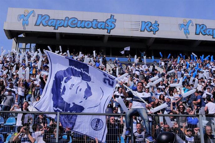 15 September 2019, Argentina, Buenos Aires: Fans of Gimnasia y Esgrima La Plata hold a flag with the likeness of their coach Diego Maradona during the Argentine Primera Division soccer match between Gymnastics and Fencing La Plata and Racing Club at the