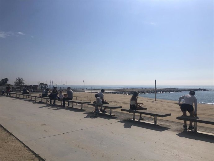 Adultos y niños mantienen la distancia de seguridad en una playa de Barcelona, en el primer día en el que se permite salir a pasear con los menores desde la declaración del estado de alarma por el coronavirus.