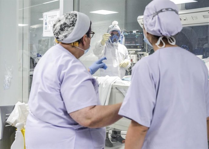Trabajadores sanitarios totalmente protegidos atienden a un paciente con coronavirus ingresado en la UCI del Hospital Arnau de Vilanova, en Valencia, Comunidad Valenciana, (España), a 24 de abril de 2020.