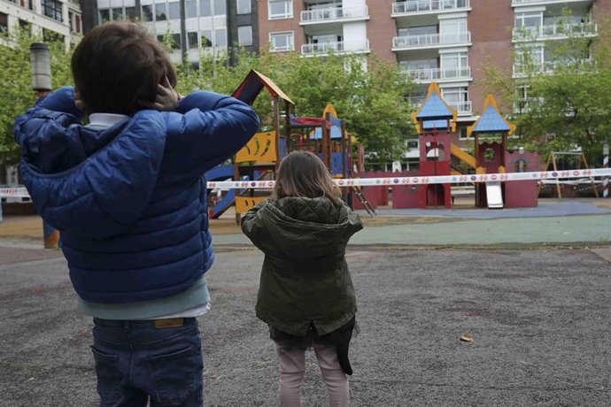 Un niño y una niña frente a un parque infantil clausurado, el primer día en el que los menores de 14 años pueden salir a la calle, en Bilbao (País Vasco/España) a 26 de abril de 2020. 