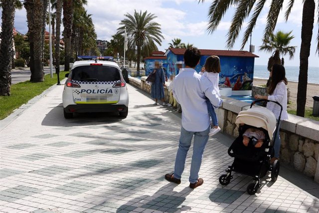 Un coche de la Policía Local de Málaga informa a viandantes en el paseo marítimo de La Malagueta en el primer día de paseo con niños