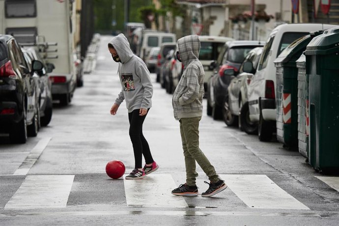 Dos niños protegidos con mascarilla juegan con una pelota por la calle en el primer día de relajamiento de las medidas de confinamiento marcadas por el Gobierno de España durante el Estado de Alarma ocasionado por la Pandemia Covid-19.