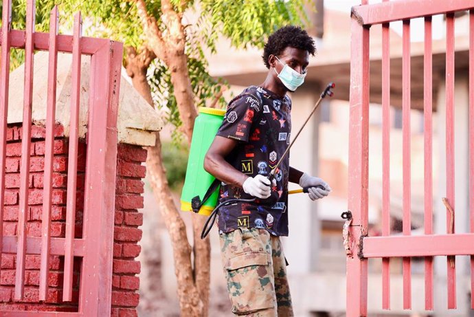 Un hombre con mascarilla desinfectando una mezquita en Sudán
