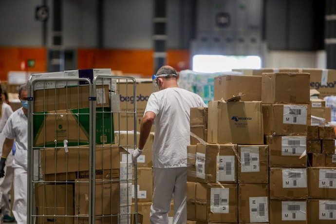 Trabajadores sanitarios protegidos con mascarilla mueven cajas en el interior del almacén habilitado en el hospital provisional de IFEMA para pacientes con Covid-19.