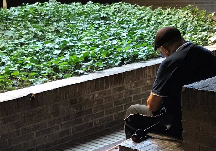 Una persona mayor descansa en un banco de la calle (Imagen de archivo)