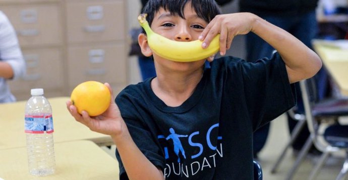 Un niño beneficiario de las actividades de la Gasol Foundation juega con dos piezas de fruta