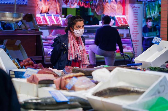 Una ciudadana compra con mascarilla flamenca en el Mercado de Triana