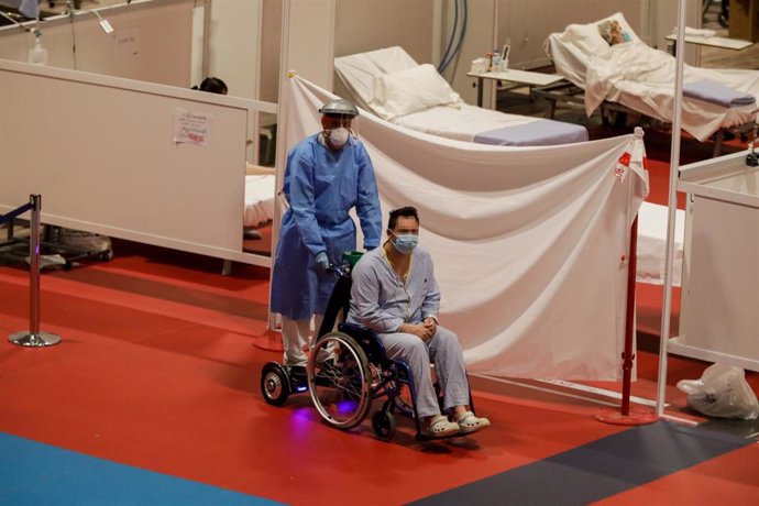 Un sanitario traslada a un paciente en silla de ruedas en el Pabellón 9 del hospital de campaña de Ifema
