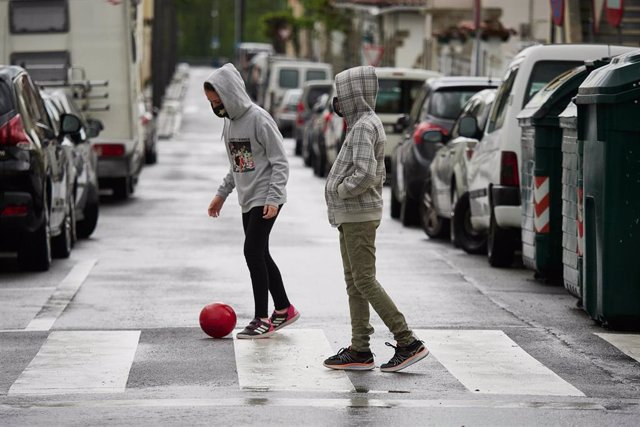 Dos niños protegidos con mascarilla juegan con una pelota por la calle en el primer día de relajamiento de las medidas de confinamiento marcadas por el Gobierno de España durante el Estado de Alarma ocasionado por la Pandemia Covid-19  en Abril 26, 2020 e
