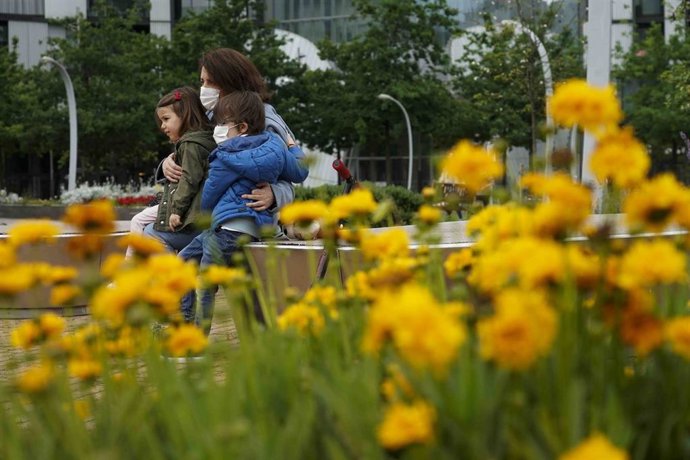 Una mujer sentada junto a una niña y un niño en el primer día en el que los menores de 14 años pueden salir a la calle, en Bilbao (País Vasco/España) a 26 de abril de 2020. Este domingo se ha comenzado a aplicar la medida de relajamiento del confinamien