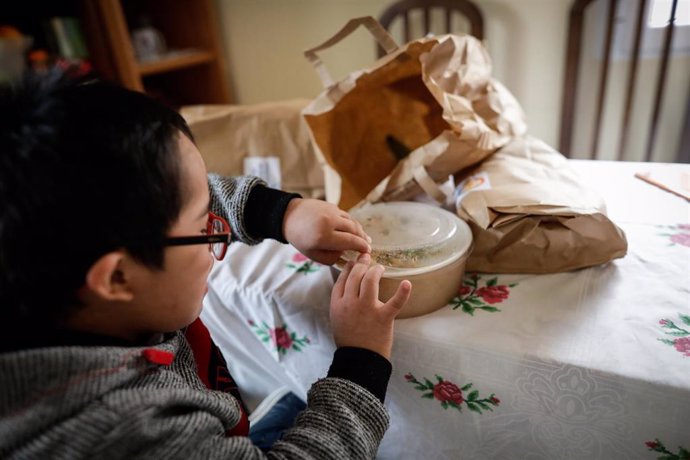 Un niño abre la tapa de un plato del menú de la ONG del chef José Andrés, que reparte en Madrid a las familias más necesitadas durante el estado de alarma provocado por el coronavirus, en Madrid (España) a 14 de abril de 2020.
