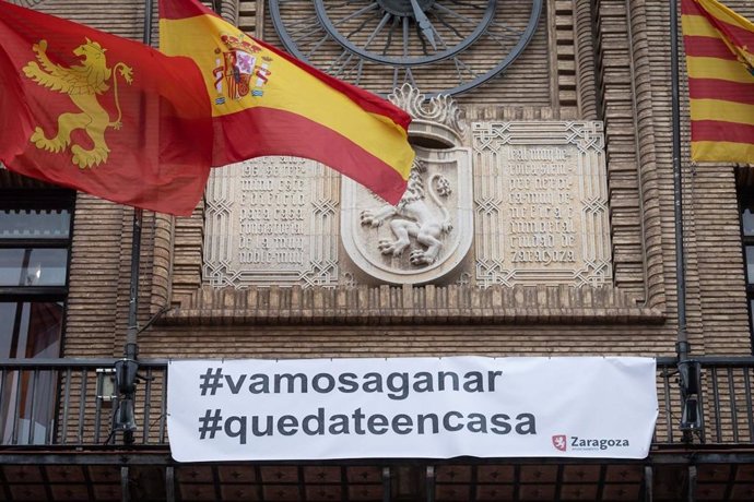 Primer plano de la pancarta con el lema "#vamosaganar" "#quedateencasa'  para animar a combartir el coronavirus cuelga  del balcón del Ayuntamiento de Zaragoza