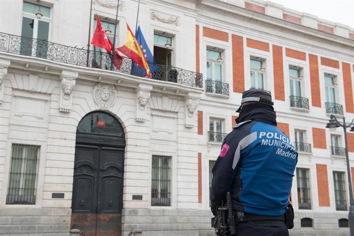 Un agente de la Policía Municipal mira la fachada de la Real Casa de Correos, sede de la Comunidad de Madrid