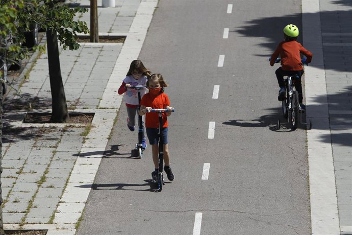 Dos niñas montan en patinete y un niño en bicicleta en Palma.