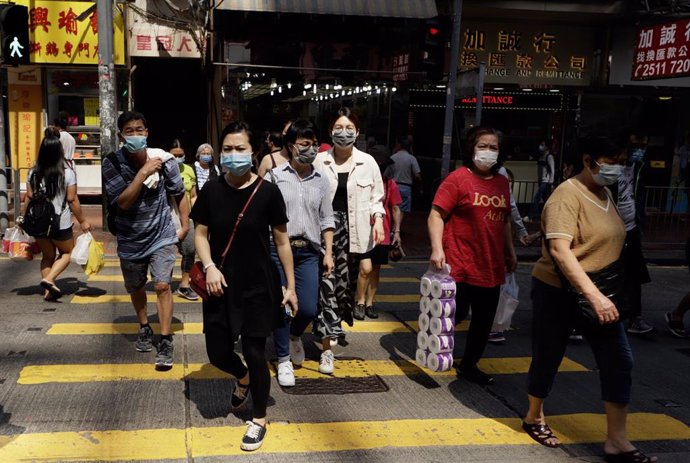 Varias personas caminan ataviadas con mascarillas por una calle de Hong Kong.
