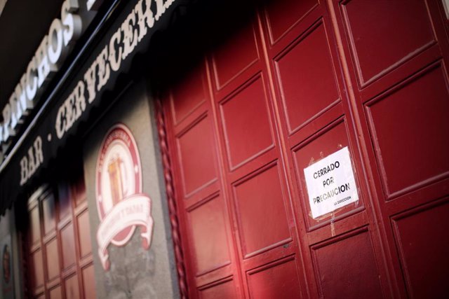 Entrada cerrada de un bar en el que un cartel dice 'Cerrado por precaución'