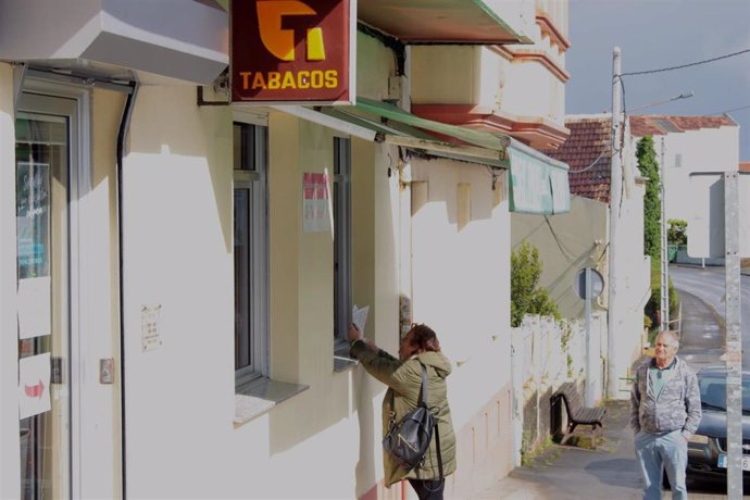 Una mujer compra el periódico en un quiosco de un pueblo gallego
