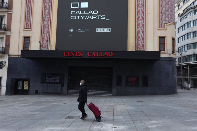 Una persona con mascarilla pasa junto a la entrada de los Cines Callao a 13 de abril de 2020.