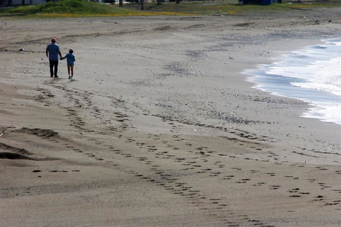 Niño con un adulto en la playa de La Malagueta el primer día en el que los menores de 14 años pueden salir, en Málaga (Andalucía ,España) a 26 de abril de 2020.
