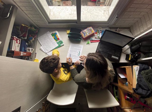 Un niño estudia y hace los deberes en casa con la ayuda de su madre, en Madrid (España) a 15 de abril de 2020.