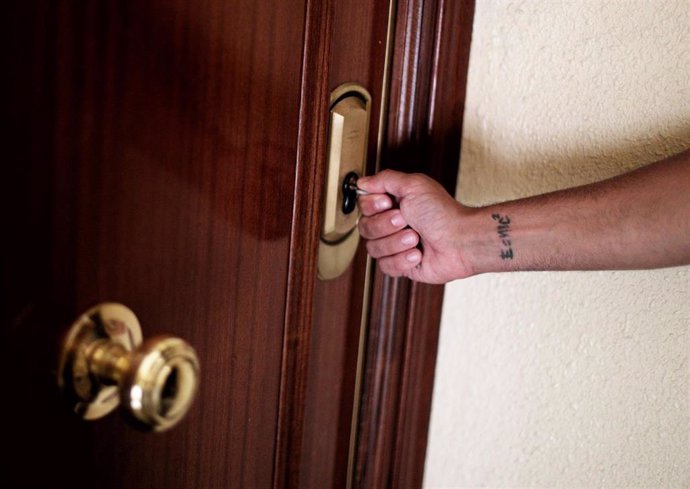 Un hombre introduce una llave en la cerradura de la puerta de una vivienda.
