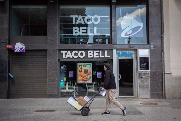 Un repartidor pasa por delante de un establecimiento de la cadena de restaurantes Taco Bell durante el día 45 del estado de alarma decretado por el Gobierno por la pandemia del Covid-19, en Barcelona/Catalunya (España) a 28 de abril de 2020.