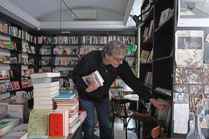 El librero y hermano de Fernando Trueba, Jesús Trueba, coloca libros de su librería 'La Buena Vida- Café del Libro', ubicada en la madrileña Calle de Vergara