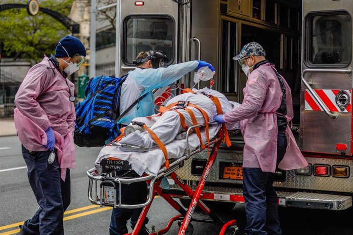 Trabajadores sanitarios trasladan a un paciente con respirador en una ambulancia en Nueva York