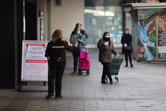 Una trabajadora de seguridad da indicaciones a las personas que esperan para entrar a uno de los supermercados de la capital durante la Semana Santa, en la que es ya la cuarta semana de confinamiento por la crisis del coronavirus en España, en Madrid, (