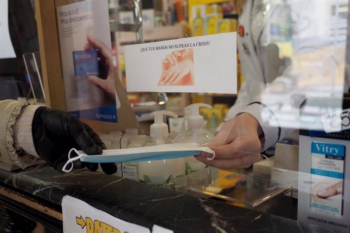 Una persona coge una mascarilla que le da una trabajadora de una farmacia de Vitoria, durante el día 46 de estado de alarma por la crisis del Covid-19. En Vitoria, País Vasco, (España), a 29 de abril de 2020.