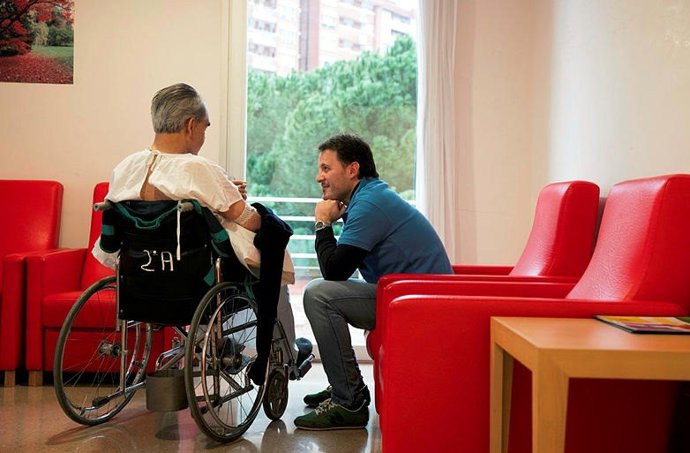 Un voluntari, parla amb un anci, en una imatge d'arxiu
