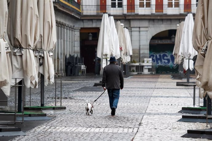 Un hombre pasea a su perro por la vaca Plaza Mayor de Madrid durante el sexto da del estado de alarma por coronavirus, en Madrid (Espaa) a 21 de marzo de 2020.