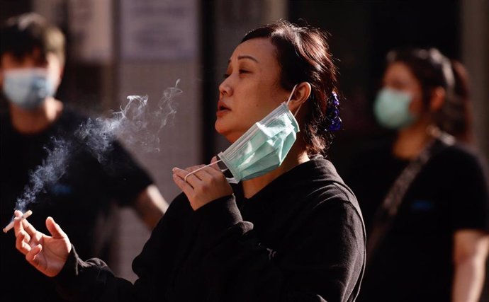 Una mujer en Hong Kong se retira la mascarilla para disfrutar de un cigarro.