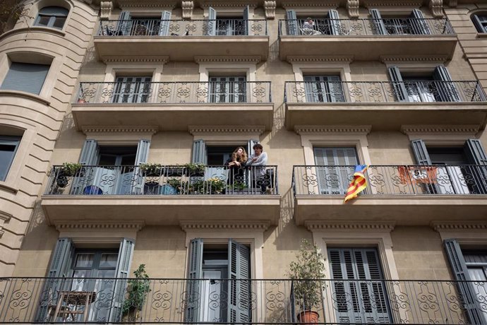 Dos personas se asoman al balcón durante el tercer día laborable del estado de alarma por coronavirus, en Barcelona/Catalunya (España) a 18 de marzo de 2020.