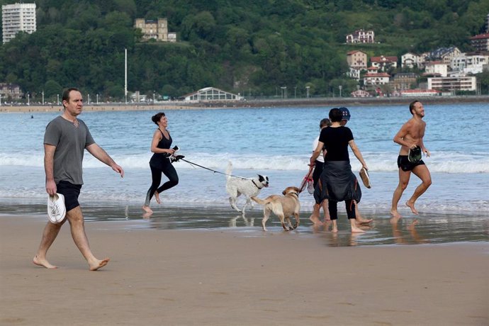 Varias persona caminan y corren con perros en la playa de La Concha en el día en que el Gobierno permite salir a hacer deporte de forma individual y pasear con otra persona con la que se conviva. En San Sebastián / Guipúzcoa (España), a 2 de mayo de 202