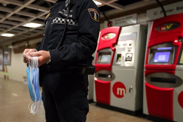 Un agente de policía local de Valencia se prepara para entregar mascarillas en el metro 