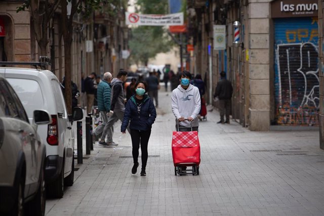Dos personas protegidas con mascarillas durante el segundo día laborable del estado de alarma por el coronavirus, en Barcelona (España), a 17 de marzo de 2020.