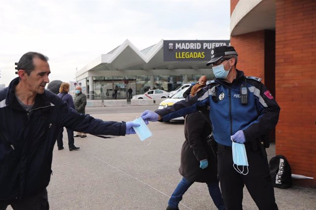 Agentes de policía municipal de Madrid entregan mascarillas a pasajeros en las inmediaciones de la estación de Cercanías de Atocha.