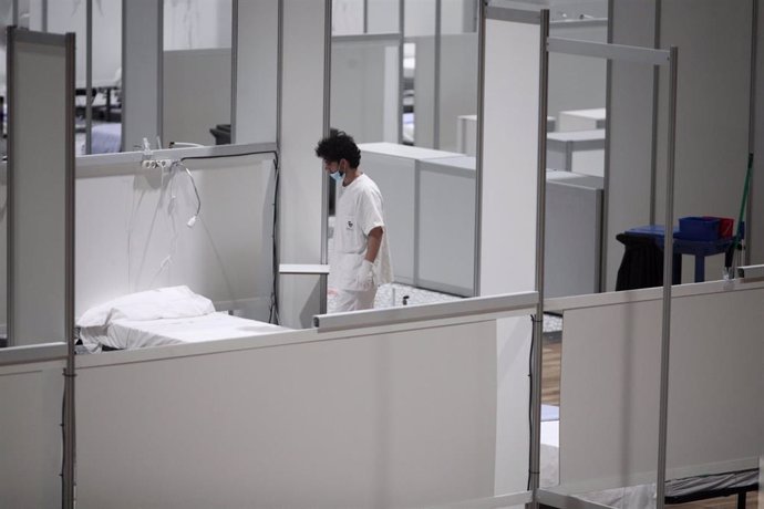 Un profesional sanitario frente a una cama vacía en el interior del hospital de campaña de IFEMA durante su último día de funcionamiento por la bajada de la presión asistencial. 