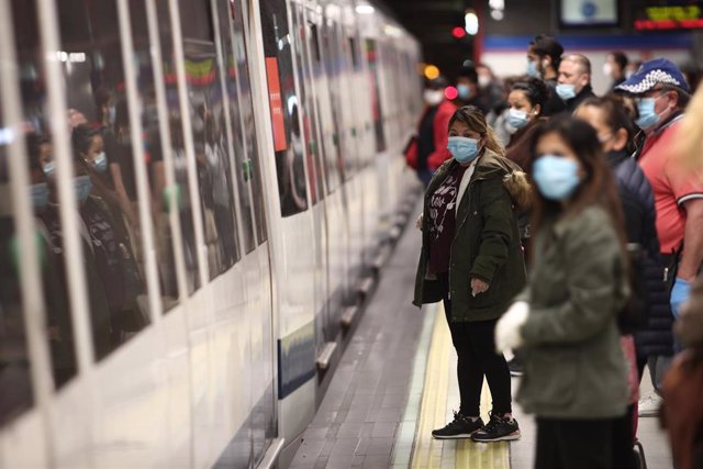 Viajeros con mascarillas en un andén de la estación de metro de Nuevos Ministerios