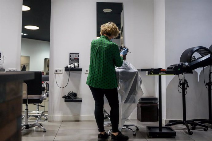 Una empleada de la peluquería Krackhair (C/Embajadores, 3, Madrid) abierta durante el día 51 del estado de alarma tiñe el pelo a una clienta. 