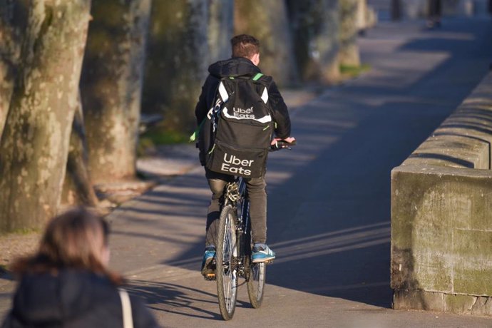 March 25, 2020 - Paris, France: A man on a bicycle doing food delivery for Uber Eats, rides on the quay of the Seine river, during the lockdown against the spread of coronavirus. (Mehdi Chebil/Contacto)